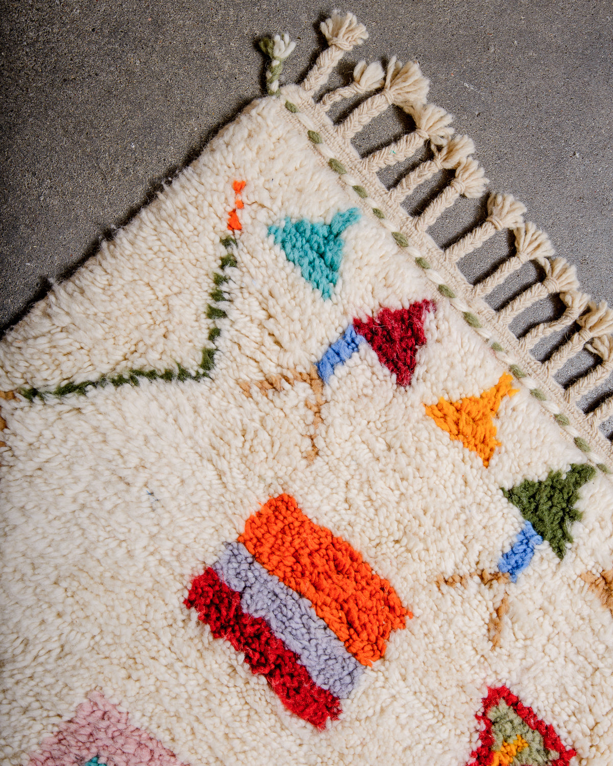 Corner of beniourain rug with natural wool tassels.